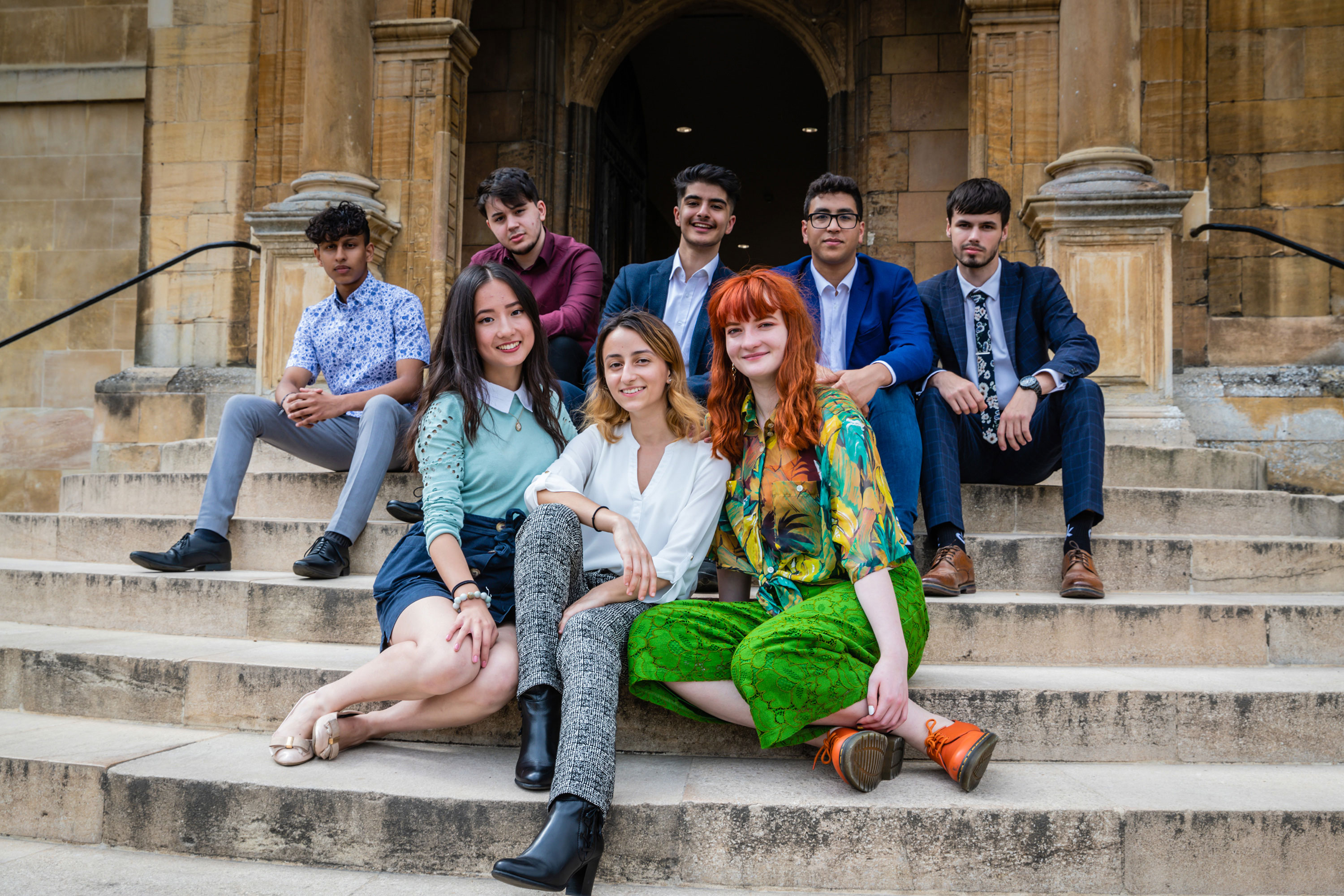 Students sitting on stairs outside of a building.