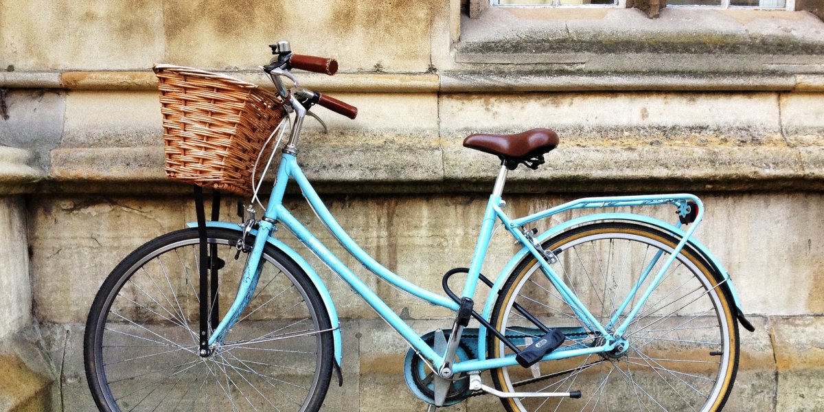 A blue dutch style bicycle leaning against a stone wall