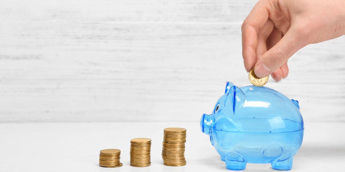 Money in stacks and an empty blue, semi transparent piggy bank.