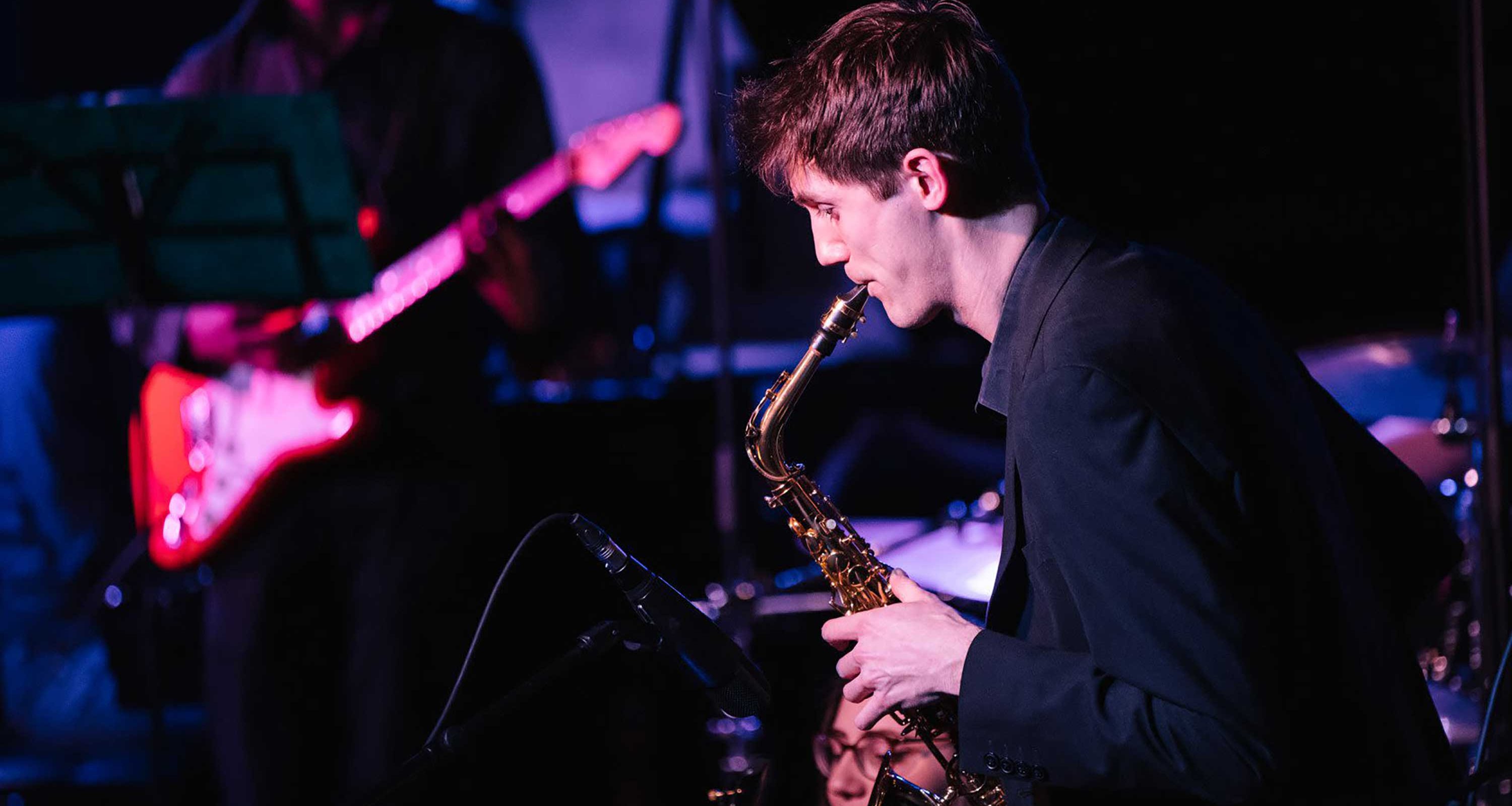 A saxophonist plays during a performance with moody lighting