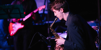 A saxophonist plays during a performance with moody lighting