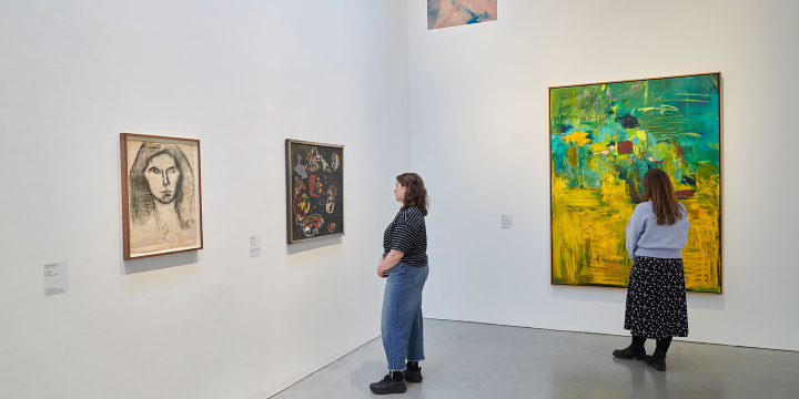Two people standing in a gallery space at Kettle's Yard looking at artworks hanging on the wall.