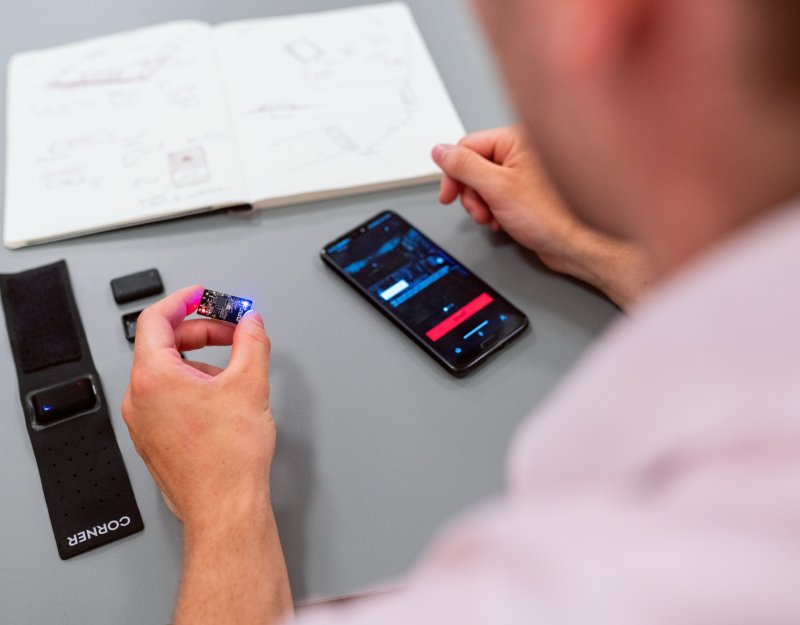 A person holds a computer chip in their left hand and a mobile phone is visible in front of them 