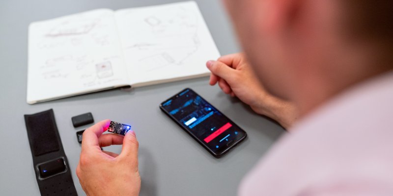 A person holds a computer chip in their left hand and a mobile phone is visible in front of them 