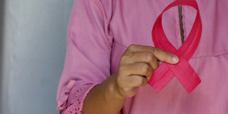 Woman holds pink breast cancer awareness ribbon. 
