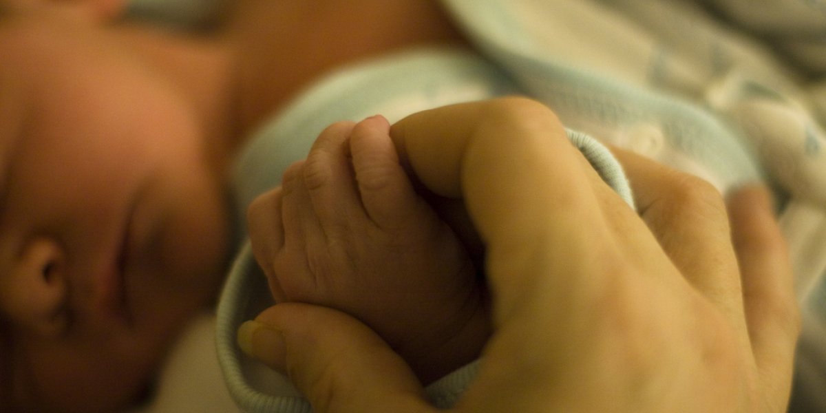 Mother holding hands with a newborn baby