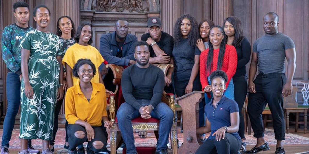 Stormzy seated and surrounded by students from the University of Cambridge Afro-Caribbean Society